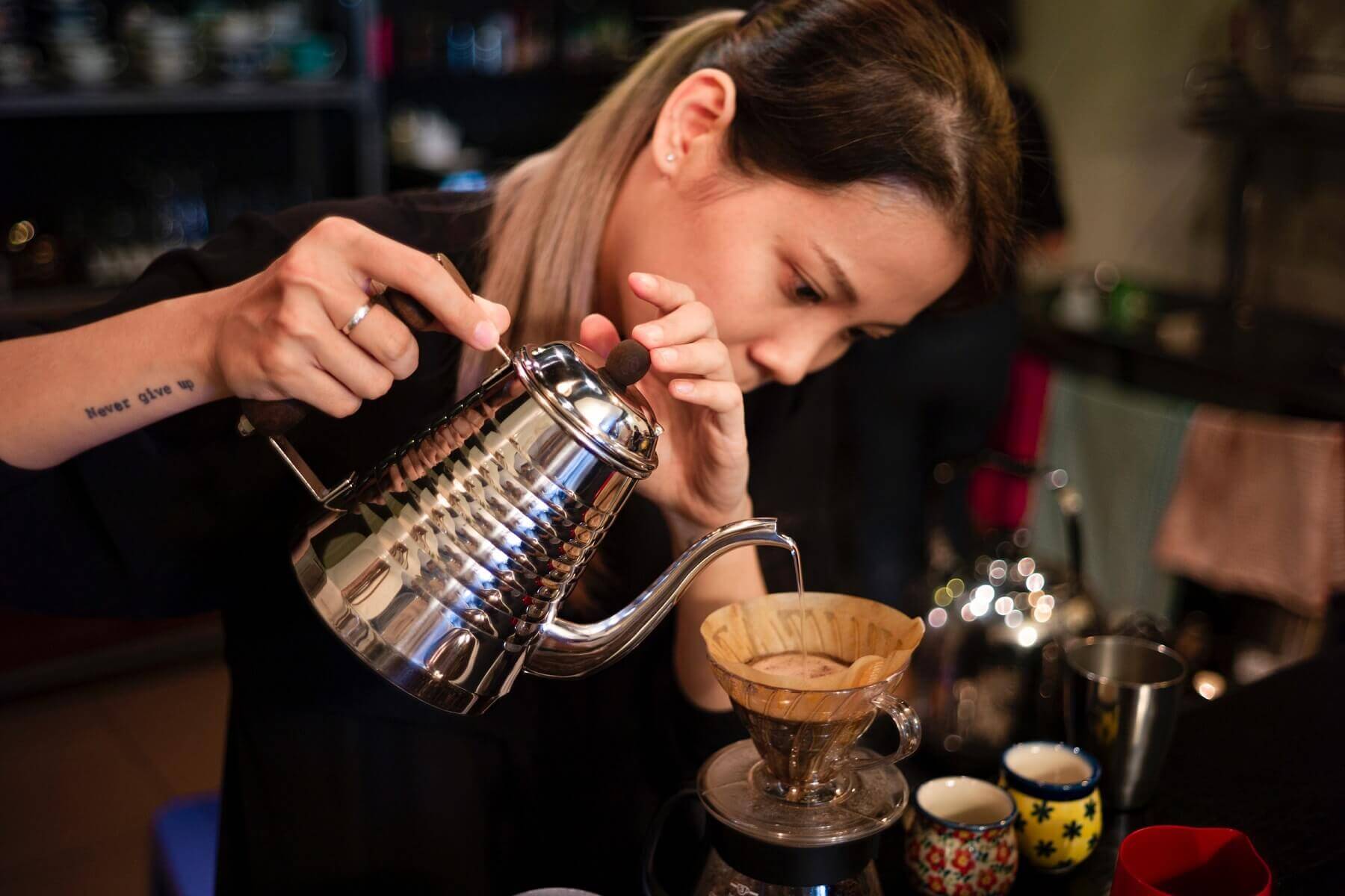 a woman is using pour over coffee kettle